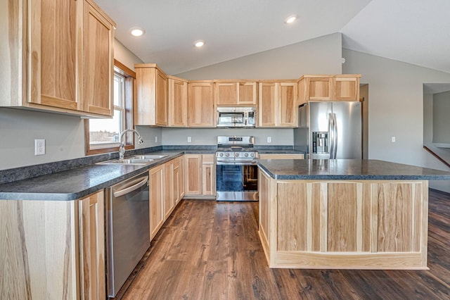 kitchen with dark countertops, light brown cabinets, appliances with stainless steel finishes, and a sink