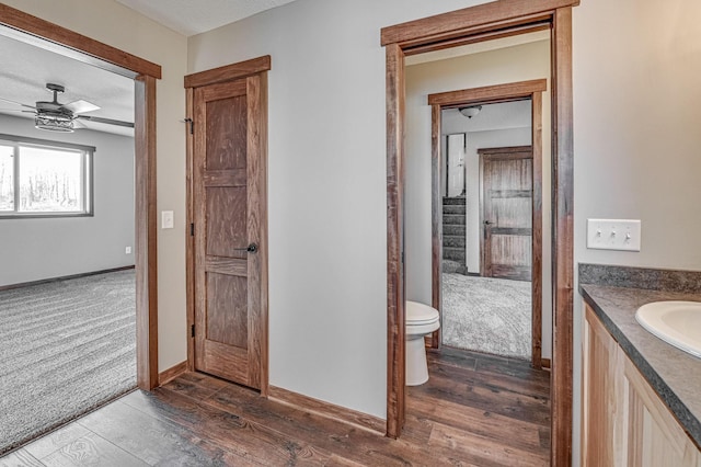 bathroom with hardwood / wood-style floors, vanity, toilet, and a ceiling fan