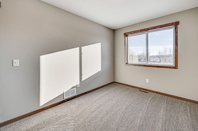 carpeted spare room with visible vents and baseboards