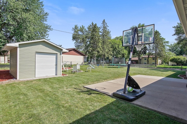 view of yard with a trampoline, fence, a garage, an outdoor structure, and a patio area