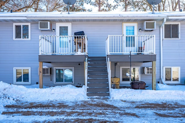 snow covered back of property with stairs and a balcony