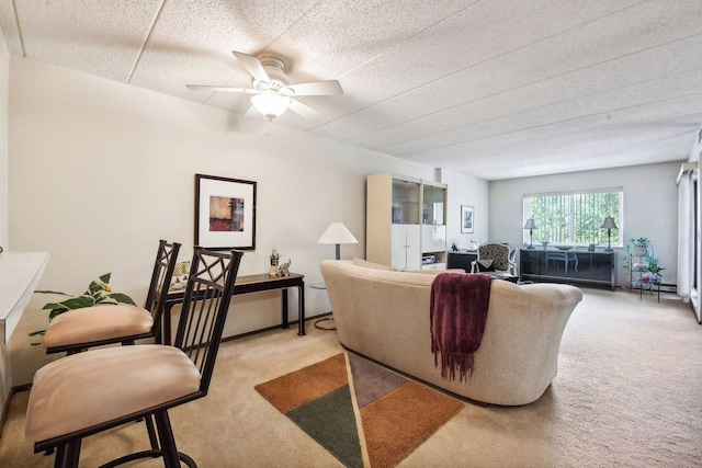 living area featuring a textured ceiling, a ceiling fan, and light colored carpet