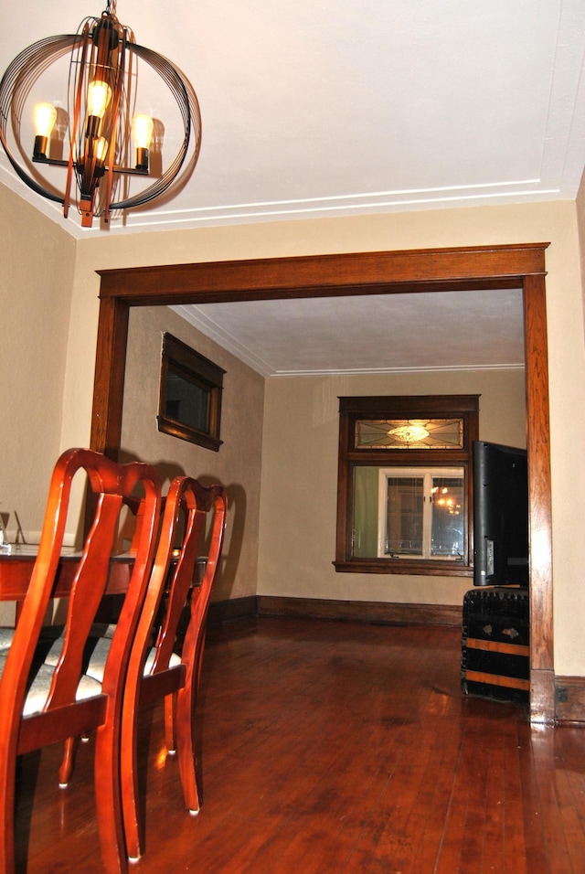 dining area featuring a notable chandelier, crown molding, baseboards, and wood finished floors