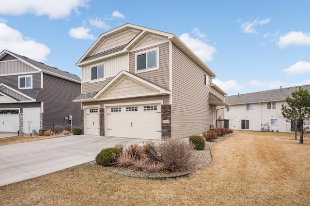 craftsman inspired home with a garage, stone siding, driveway, and a front lawn