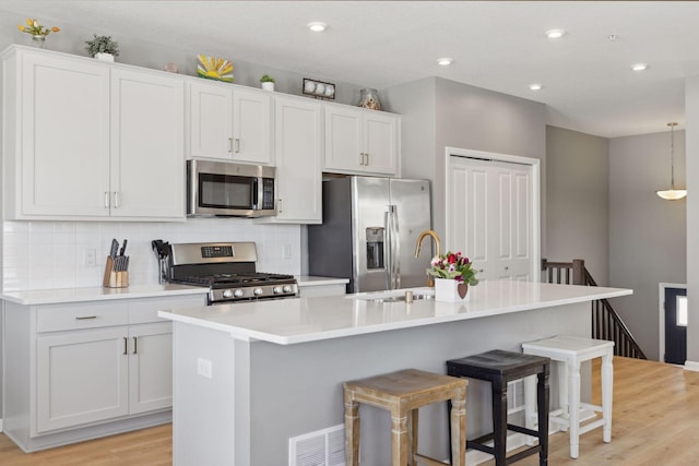 kitchen featuring light countertops, appliances with stainless steel finishes, and a center island with sink