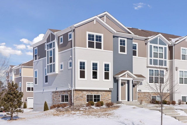 view of front facade featuring a garage, stone siding, and board and batten siding