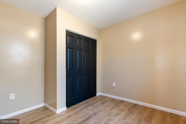 unfurnished bedroom with light wood finished floors, a closet, and baseboards