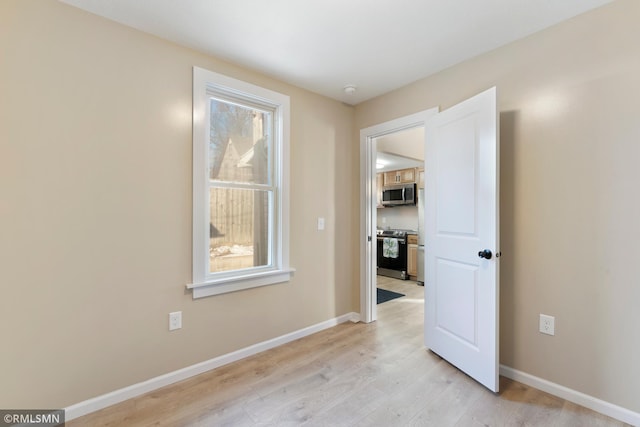 empty room featuring light wood finished floors and baseboards