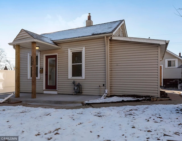 snow covered house with a garage and a chimney