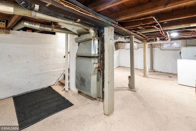 unfinished basement with heating unit and refrigerator