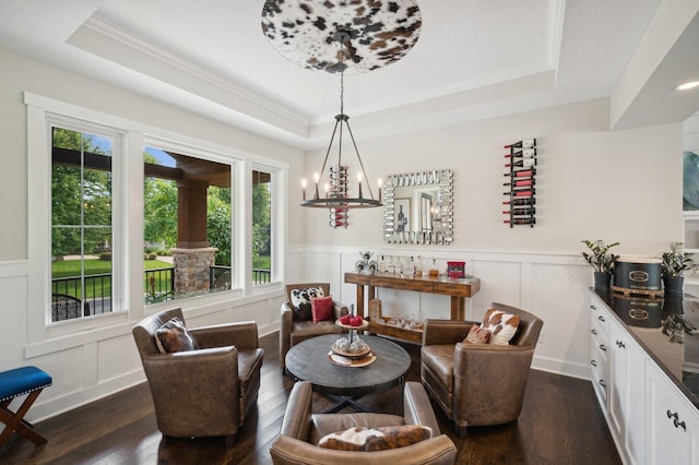 living area with dark wood-style flooring, a raised ceiling, and a decorative wall