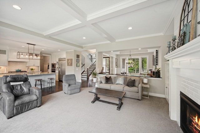 living area with baseboards, stairway, crown molding, a brick fireplace, and beam ceiling