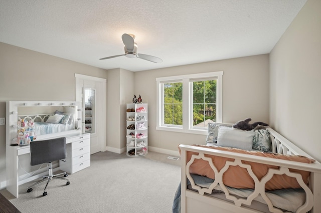 carpeted bedroom with a textured ceiling, ceiling fan, visible vents, and baseboards