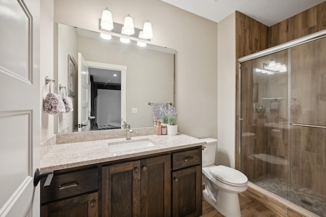 bathroom featuring toilet, a shower stall, and vanity