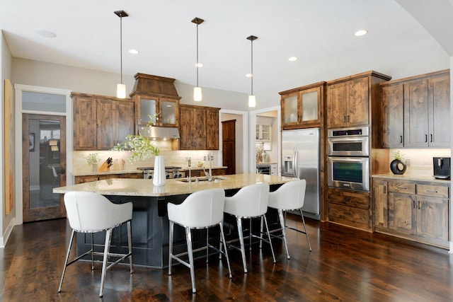 kitchen featuring glass insert cabinets, stainless steel appliances, a sink, and pendant lighting