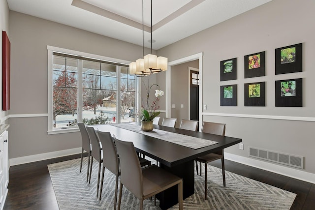 dining area with dark wood finished floors, a raised ceiling, visible vents, and baseboards