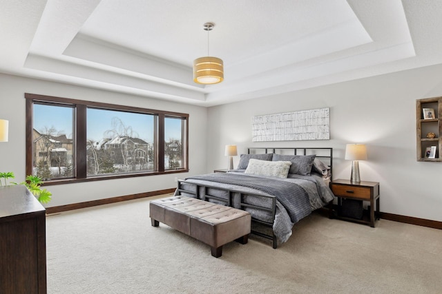 bedroom featuring a tray ceiling, light carpet, and baseboards