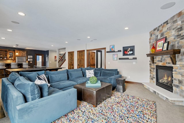 living area featuring recessed lighting, light colored carpet, a fireplace, baseboards, and stairs