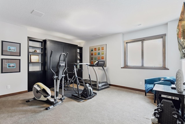 exercise area with carpet, a textured ceiling, and baseboards