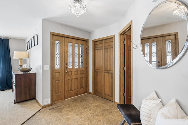 foyer entrance with visible vents, a notable chandelier, and baseboards