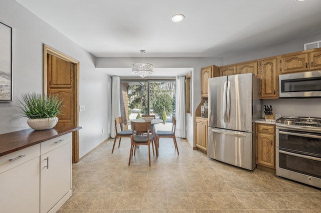 kitchen featuring decorative light fixtures, dark countertops, visible vents, appliances with stainless steel finishes, and a chandelier