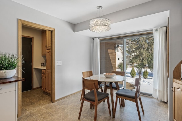 dining space featuring a chandelier and baseboards