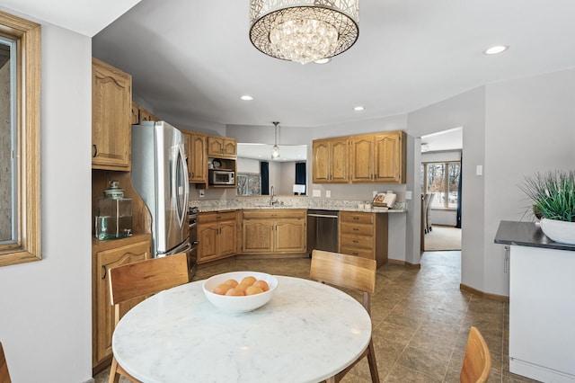 kitchen with pendant lighting, brown cabinets, light countertops, appliances with stainless steel finishes, and a sink