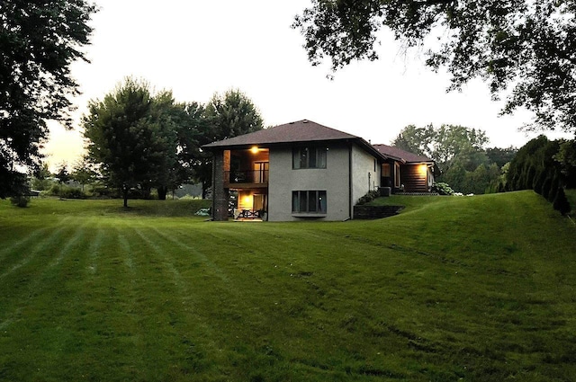 back of house featuring a balcony and a yard