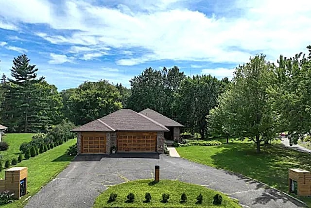 view of community with aphalt driveway, a yard, and an attached garage