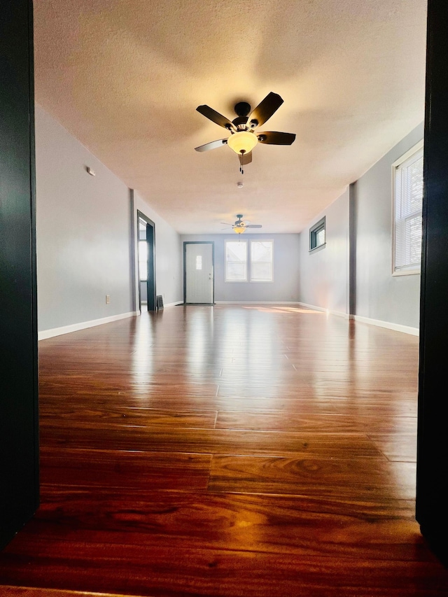 spare room featuring a textured ceiling, ceiling fan, wood finished floors, and baseboards