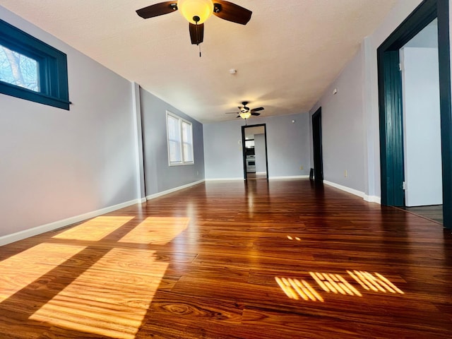 empty room with ceiling fan, baseboards, and wood finished floors