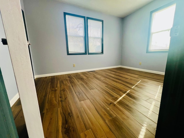 unfurnished bedroom with visible vents, baseboards, and dark wood finished floors