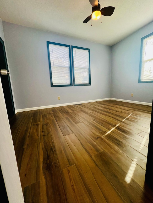 empty room with a ceiling fan, baseboards, and wood finished floors