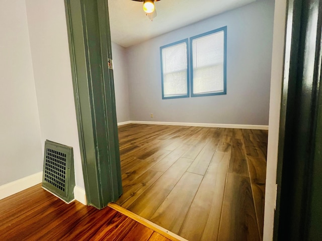 spare room featuring baseboards, visible vents, and wood finished floors