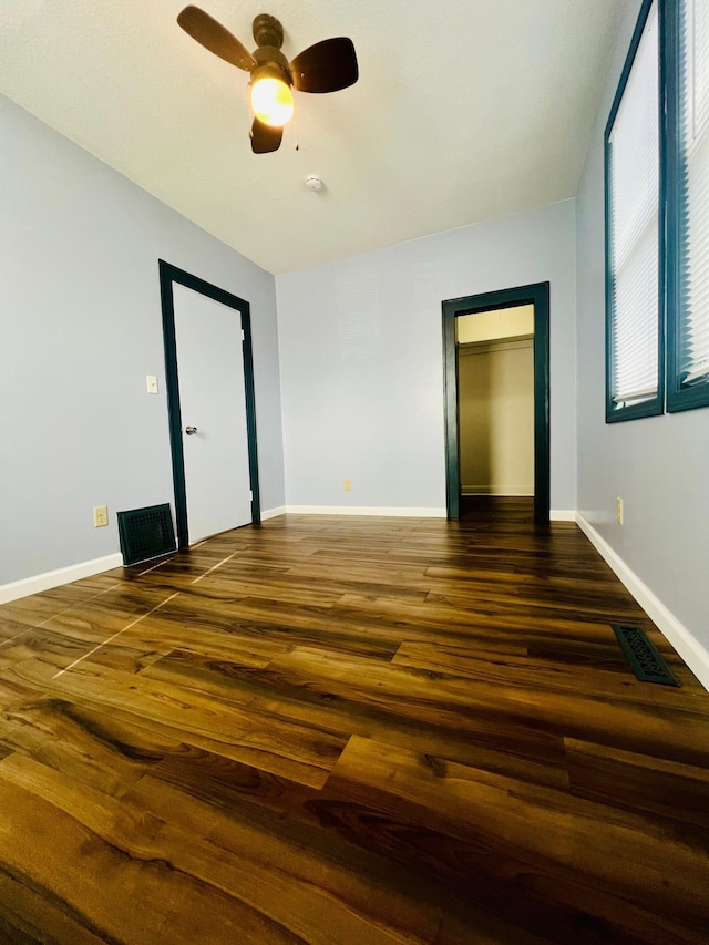 spare room with a ceiling fan, baseboards, visible vents, and wood finished floors