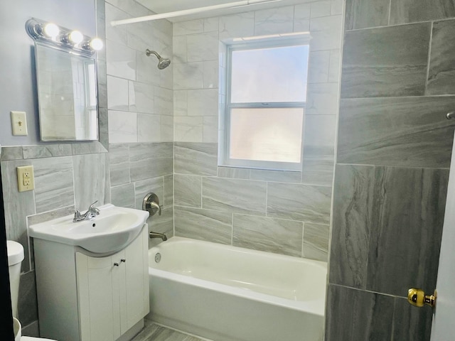 bathroom with toilet, tub / shower combination, vanity, and tile walls