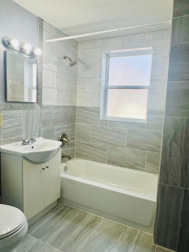 bathroom with bathtub / shower combination, toilet, vanity, tile walls, and backsplash