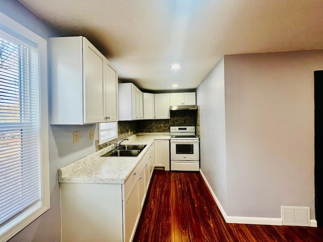 kitchen featuring white electric range oven, light countertops, visible vents, decorative backsplash, and a sink