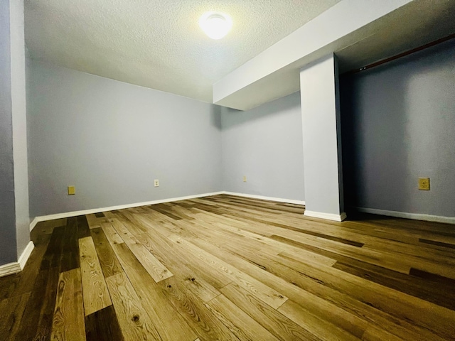 unfurnished room with hardwood / wood-style flooring, baseboards, and a textured ceiling