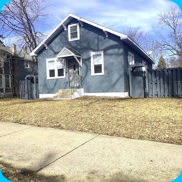 bungalow-style house with fence and stucco siding