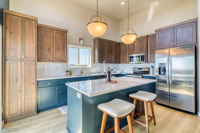 kitchen with stainless steel appliances, light countertops, hanging light fixtures, a kitchen island, and a kitchen bar