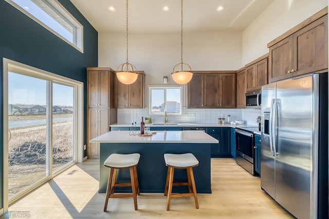 kitchen featuring stainless steel appliances, a breakfast bar, light countertops, and a kitchen island