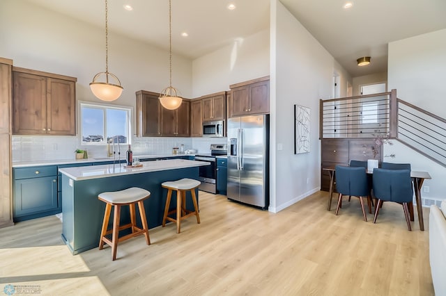 kitchen featuring a center island, decorative light fixtures, stainless steel appliances, light countertops, and light wood-style floors