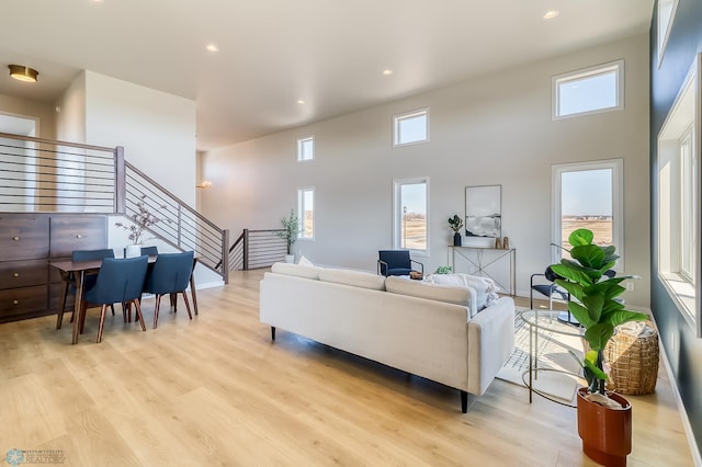 living area featuring light wood-style floors, a wealth of natural light, stairway, and recessed lighting