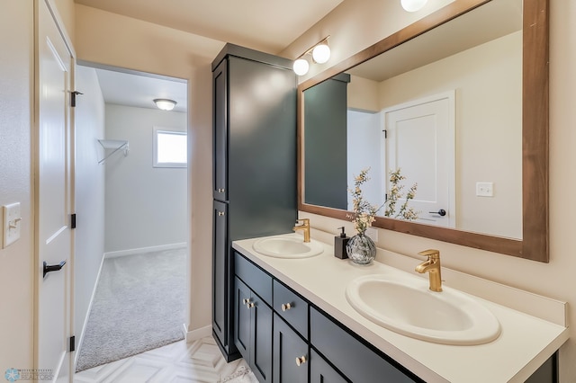 full bathroom with double vanity, a spacious closet, baseboards, and a sink