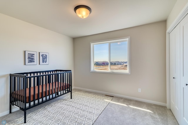 bedroom featuring a closet, light carpet, visible vents, and baseboards