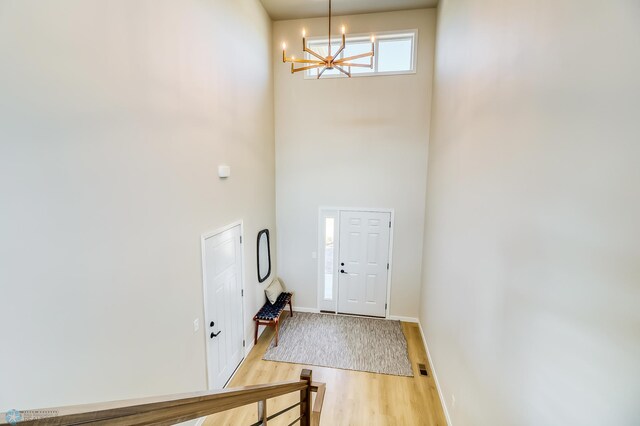 entryway with an inviting chandelier, baseboards, a high ceiling, and wood finished floors