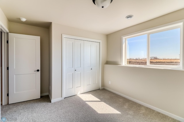 unfurnished bedroom featuring a closet, light carpet, visible vents, and baseboards