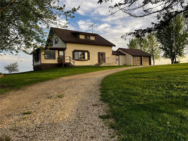 view of front of house featuring dirt driveway, a front lawn, and a garage