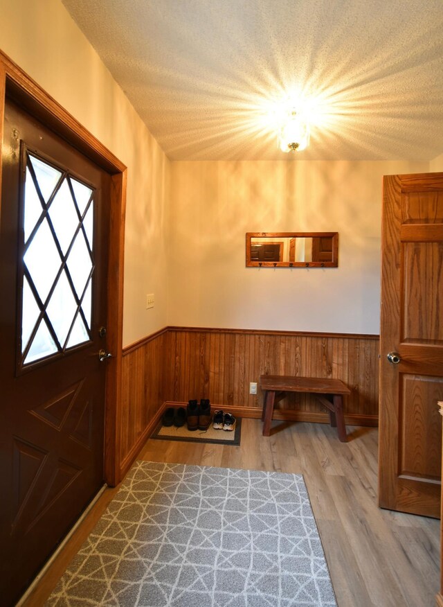 entryway featuring wood finished floors, a textured ceiling, and wainscoting